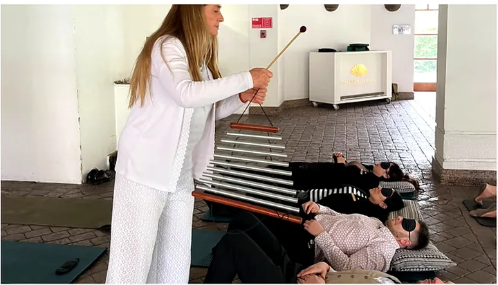 Participantes descansan sobre colchonetas durante una experiencia con instrumentos sonoros