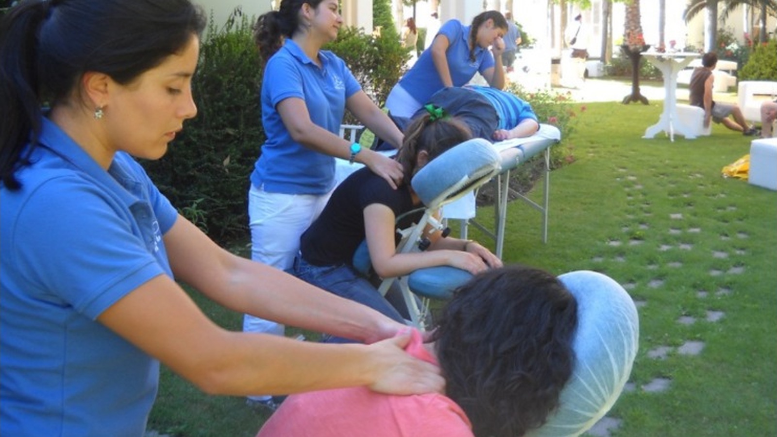 Terapeutas realizan masajes en sillas durante una actividad de bienestar al aire libre